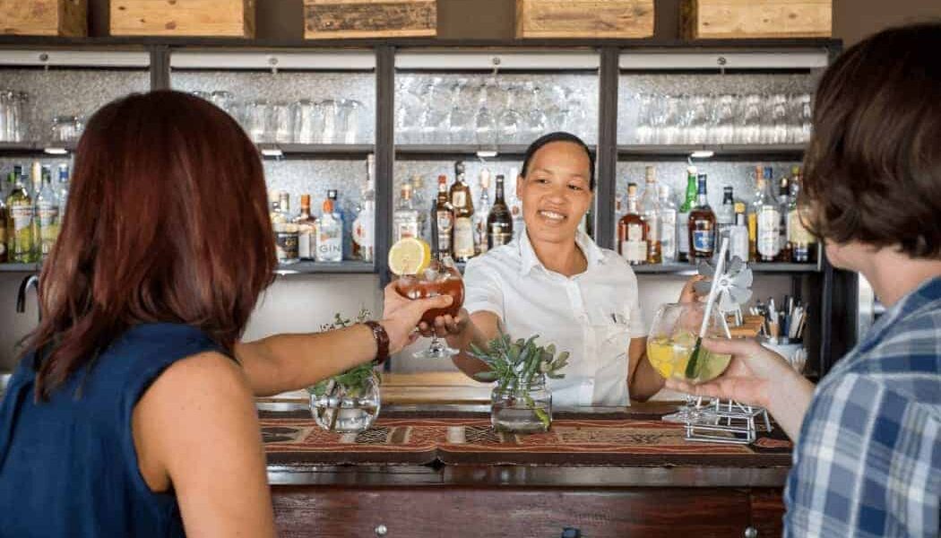 Bartender at De Zeekoe Guest House restaurant bar serving cocktails